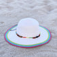 White sun hat with colorful rim on sandy ground