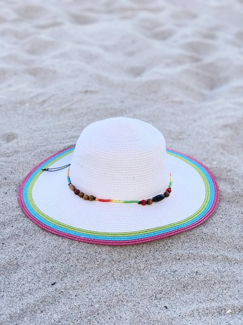 White sun hat with colorful rim on sandy ground