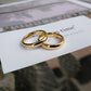 Two gold rings on a piece of paper with text in the background