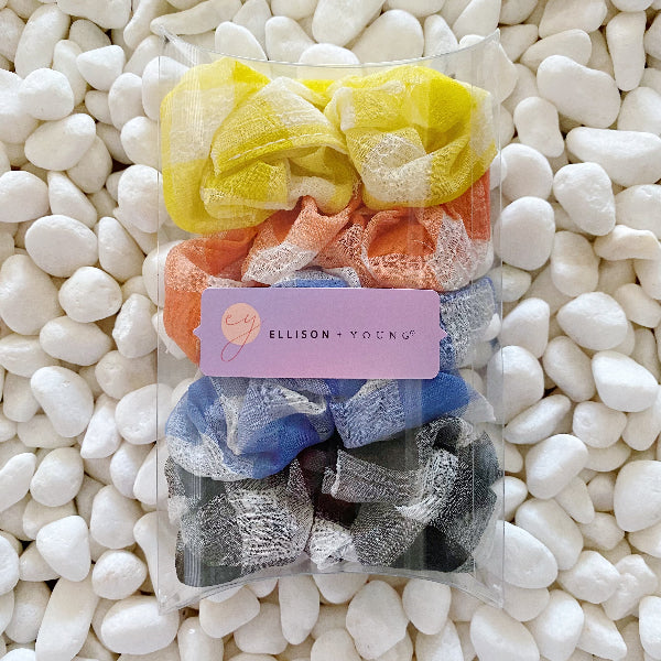 Packaged set of colorful scrunchies with 'Ellison + Young' label on pebbles