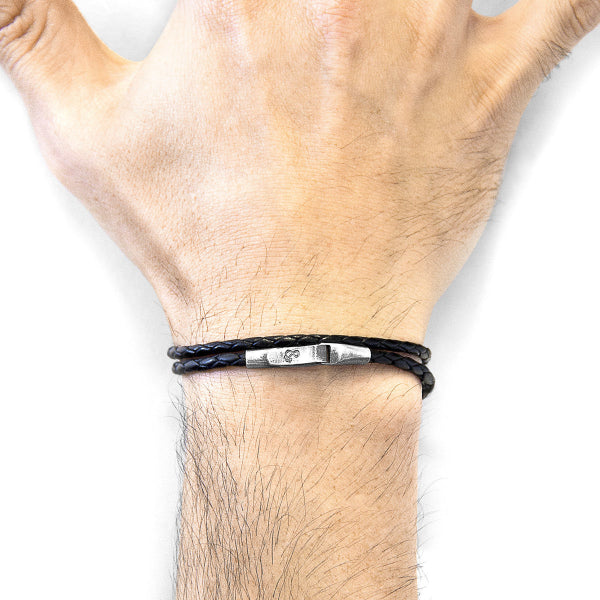 Black leather bracelet with metal clasp on a wrist against a white background