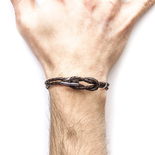 Brown braided bracelet on a wrist against a white background