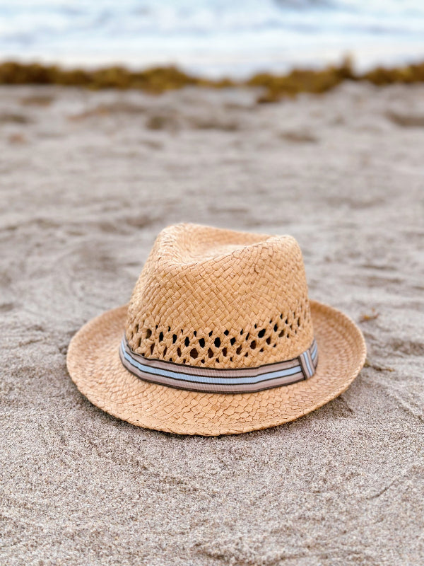 Straw hat with a ribbon on a sandy beach