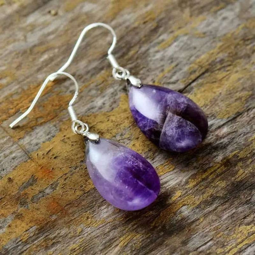 Purple teardrop earrings on a wooden surface