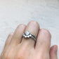Silver ring with a stone on a finger against a light background