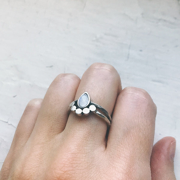 Silver ring with a stone on a finger against a light background