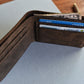 Brown leather wallet with cards and money on a light gray surface