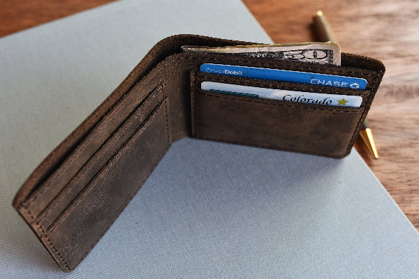 Brown leather wallet with cards and money on a light gray surface
