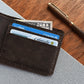 Brown leather wallet with cards and a pen on a wooden surface
