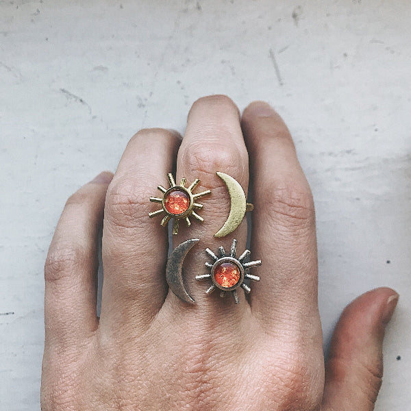 Hand wearing three rings with sun, moon, and star designs on a light background