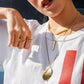 Person wearing gold necklaces and rings on a white shirt with red stripe