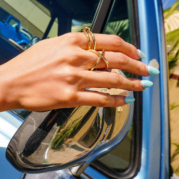 Hand with gold rings on a car mirror