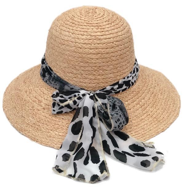 Beige straw hat with a black and white patterned scarf tied around it on a white background