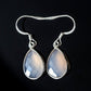 Teardrop-shaped earrings with silver hooks on a black background