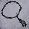 Black beaded necklace on a light gray fabric background