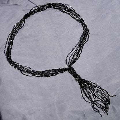 Black beaded necklace on a light gray fabric background