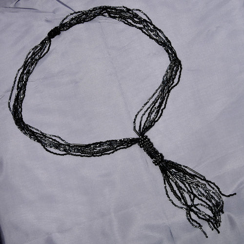 Black beaded necklace on a light gray fabric background
