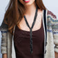 Woman wearing a patterned cardigan over a brown top with a plain background