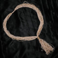 Beige headband with gold accents and tassel on a black background