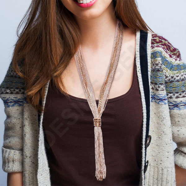 Woman wearing a patterned cardigan over a brown top with a decorative necklace.