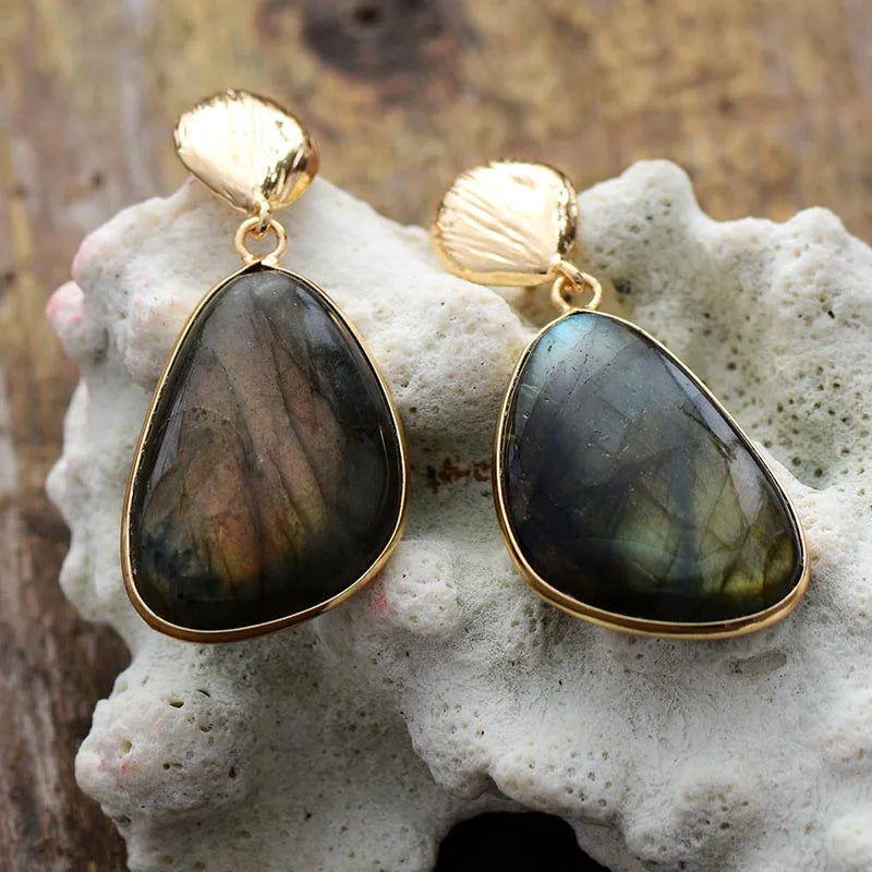Gold-framed labradorite earrings on a textured surface