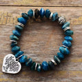 Blue beaded bracelet with a silver heart-shaped charm on a wooden surface