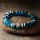 Blue beaded bracelet with a silver and gold accent on a stone surface