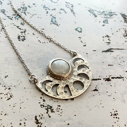 Silver necklace with a circular pendant on a textured surface