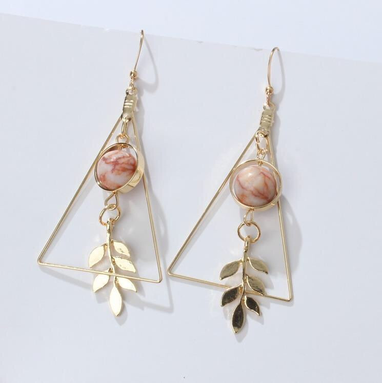 Gold triangle earrings with leaf details on a white background