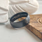 Black ring with engraved text on a wooden surface