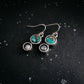 Earrings with turquoise stones and small round elements on a dark textured background