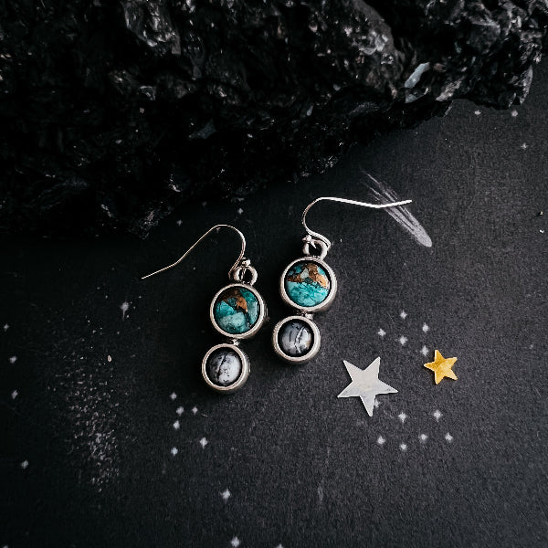 Pair of earrings with turquoise stones on a dark surface with star decorations