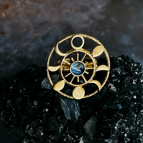 Gold ring with celestial design on a dark stone background