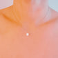 Delicate necklace with a small pendant on a soft peach background