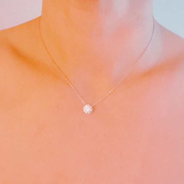 Delicate necklace with a small pendant on a soft peach background