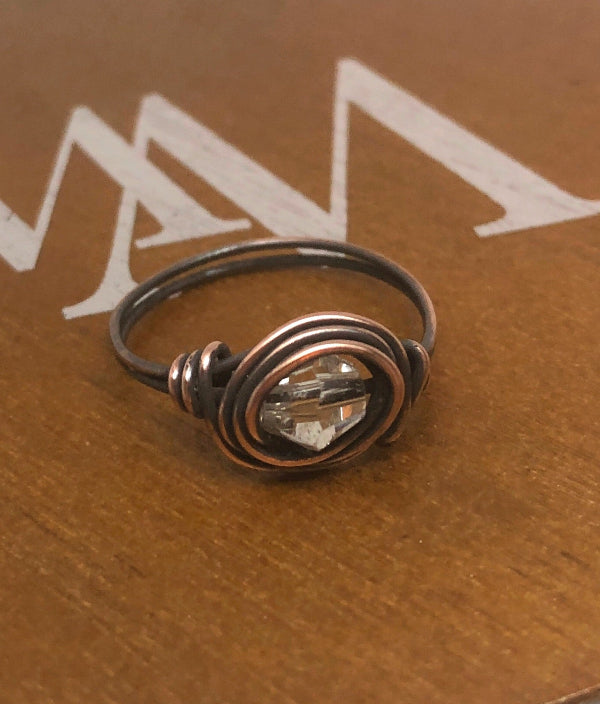 Copper ring with a clear gemstone on a brown surface