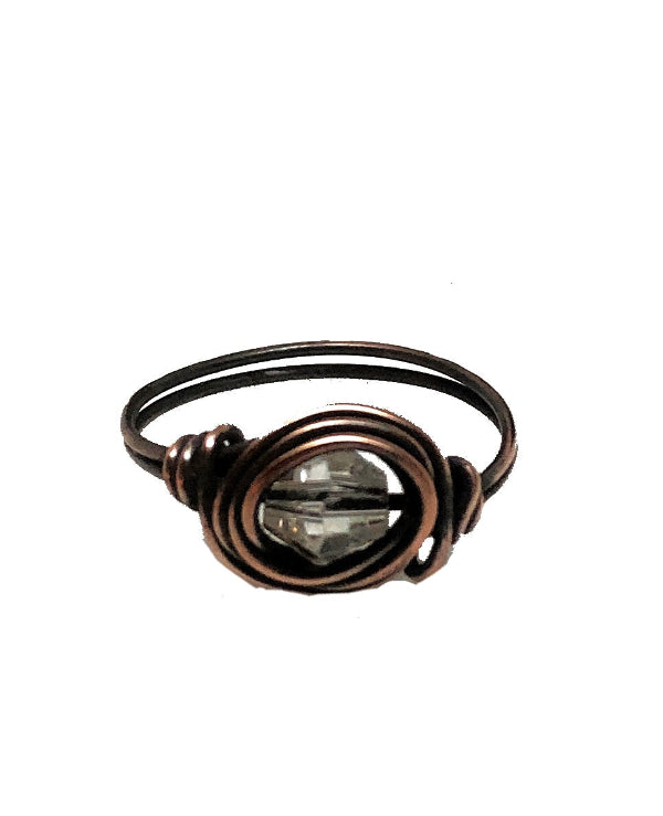 Bronze wire-wrapped ring with a clear gemstone on a white background