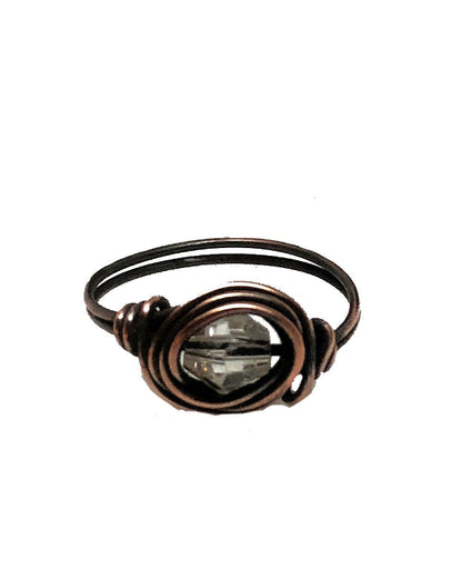 Bronze wire-wrapped ring with a clear gemstone on a white background