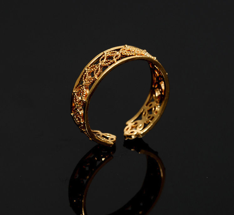 Gold bracelet with intricate design on a black background