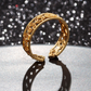 Gold bracelet with intricate design on a reflective surface with a glittery background