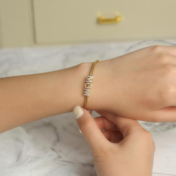 Gold bracelet with heart-shaped beads on a wrist against a marble background