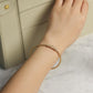 Hand wearing a gold bracelet with a marble background