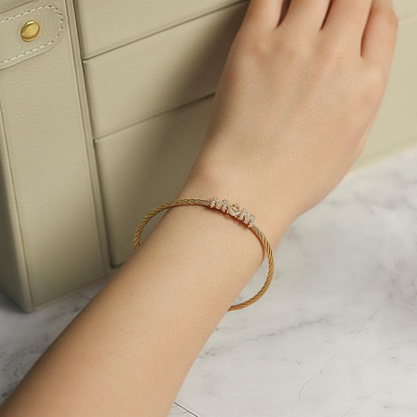 Hand wearing a gold bracelet with a marble background