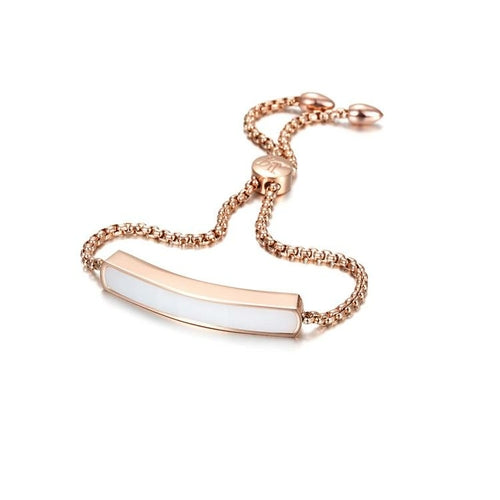 Rose gold bracelet with a white bar charm on a white background