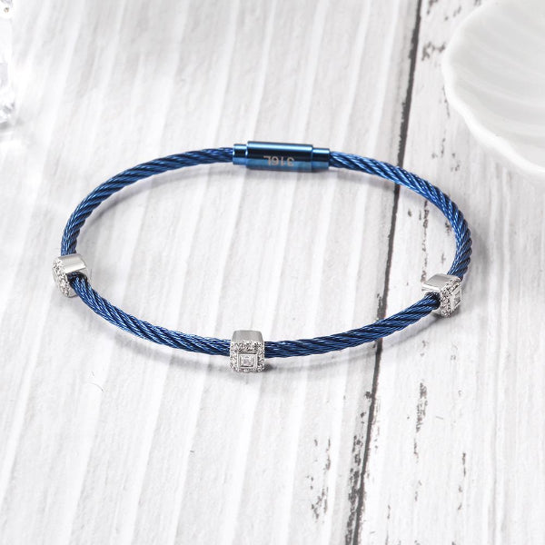 Blue braided bracelet with silver beads on a light wooden surface