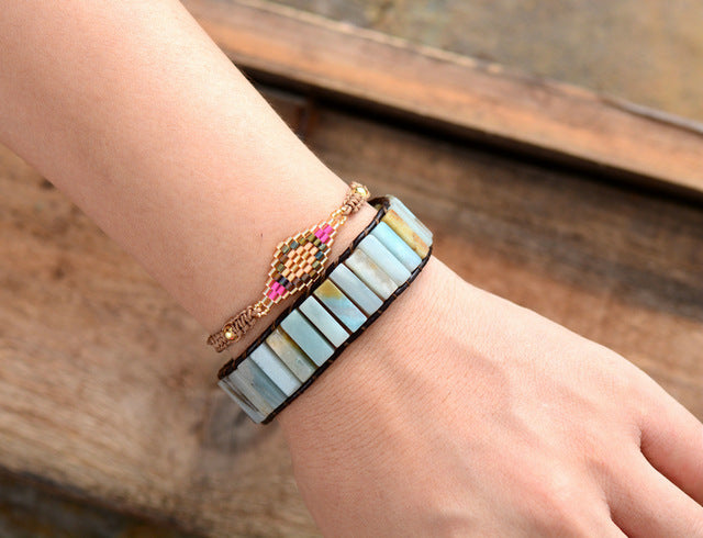 Bracelet with colorful stones on a wrist against a wooden background