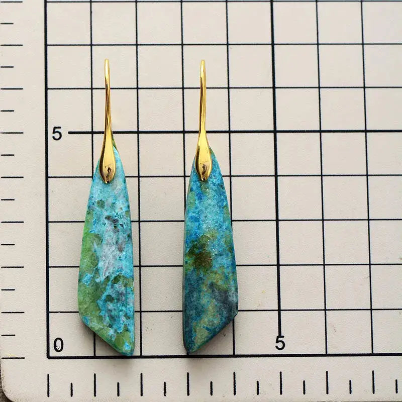 Pair of blue marbled earrings with gold hooks on a grid background