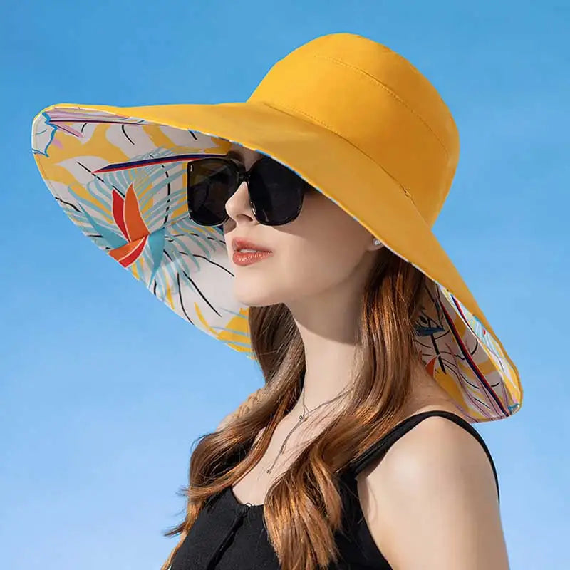 Woman wearing a yellow sun hat with a colorful floral interior against a clear blue sky.