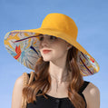 Mannequin wearing a yellow sun hat with a colorful floral interior against a blue sky.