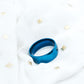 Blue silicone lid on a white surface with small decorative items around